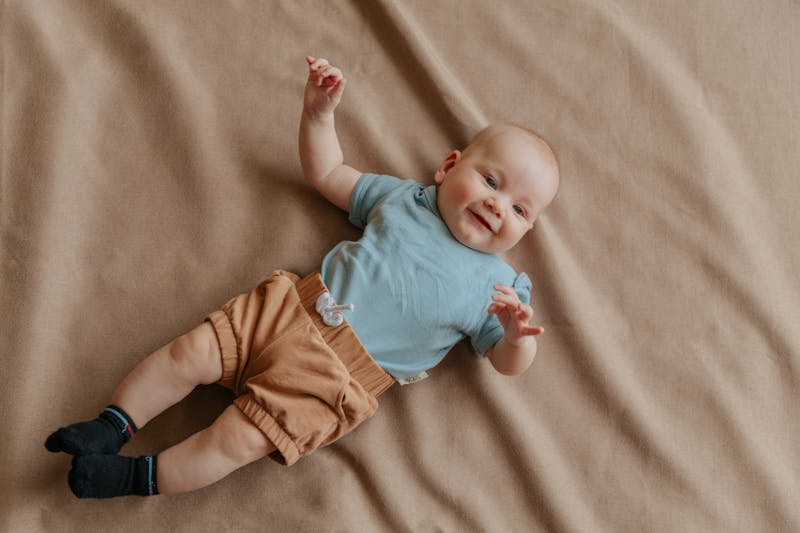Newborn jongen in comfortabele babykleding op een zachte beige ondergrond